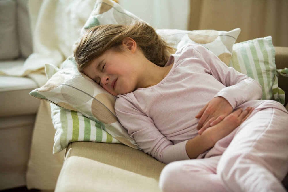 Child Lying on Sofa in the Living Room With Stomach Pain