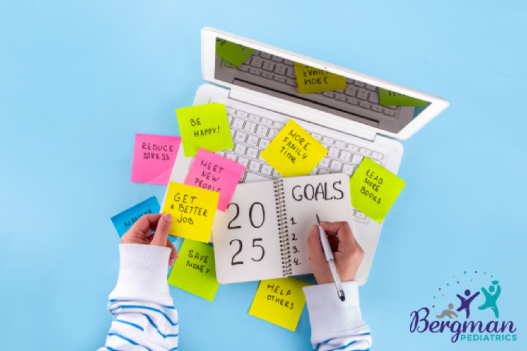 A person writes "2025 Goals" in a notebook surrounded by colorful sticky notes with goals like "Reduce Stress," "Be Happy," and "More Family Time," with a laptop and the "Bergman Pediatrics" logo in the background.