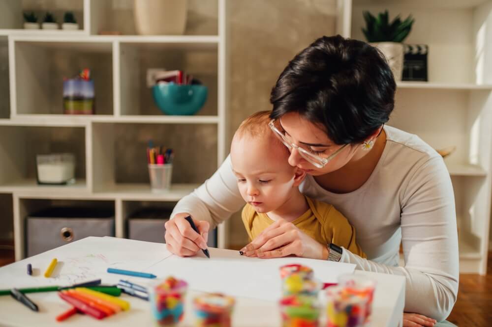 A mother and her child work on fine motor skills through the games while drawing and coloring with crayons.