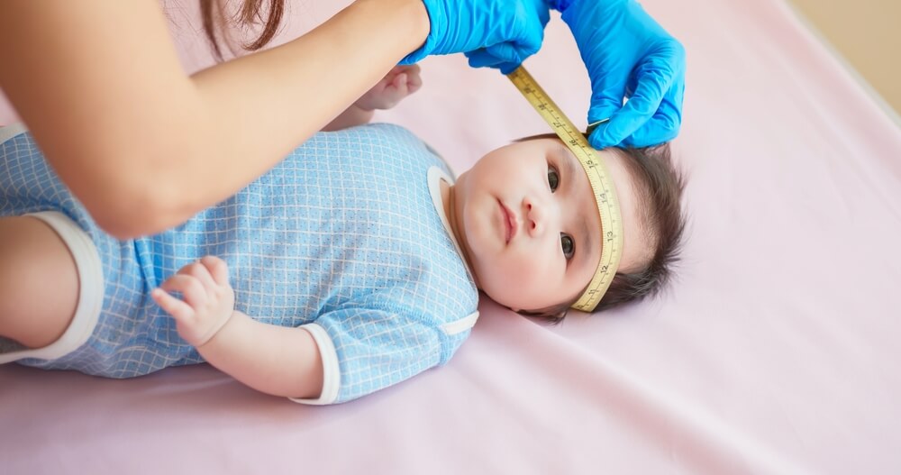 Asian Doctor Measure Baby Head by Tape to Check-up His Grow Curve and Infant Lying on Bed