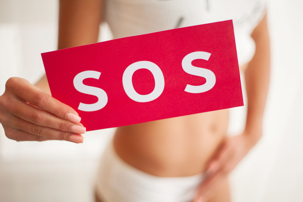 Vaginal or Urinary Infection and Problems Concept. Young Woman Holds Paper With SOS Above Crotch