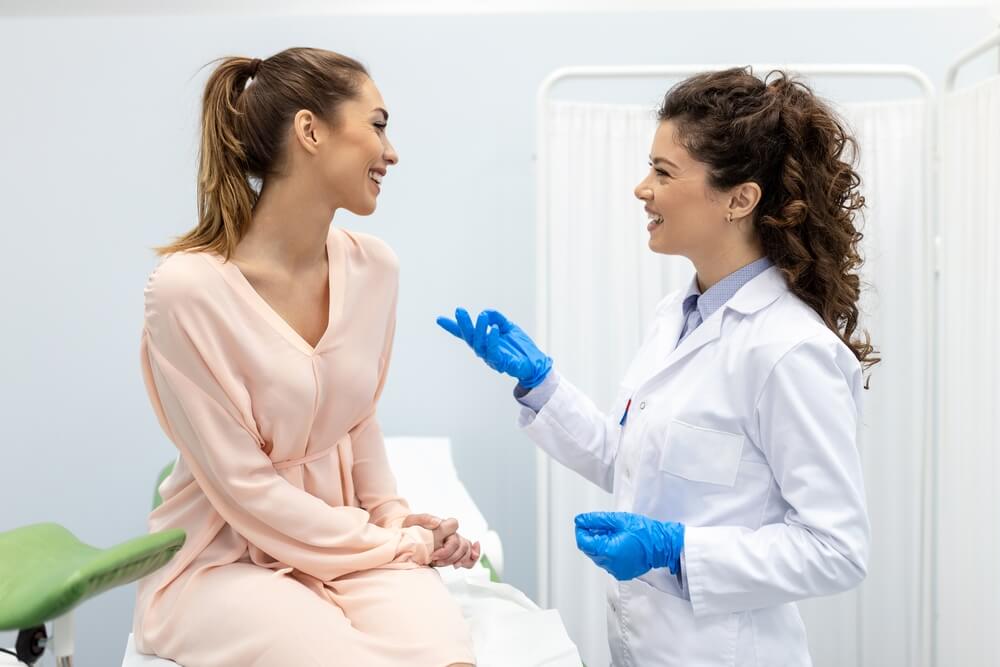 Gynecologist Talking With Young Female Patient During Medical Consultation in Modern Clinic.