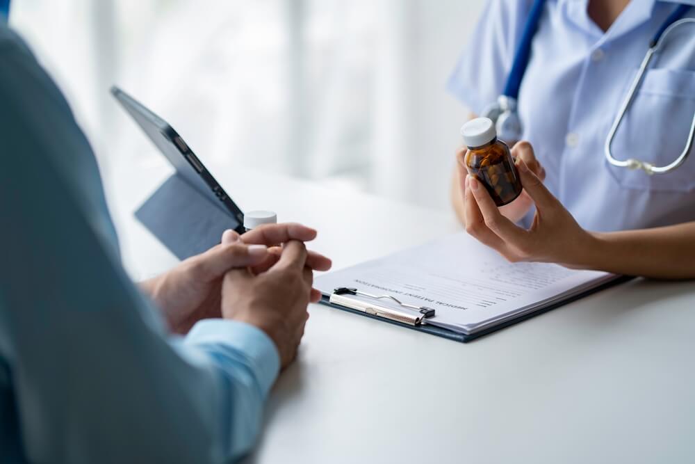 A female doctor is giving medical advice to a patient, explaining when and how to take the pills