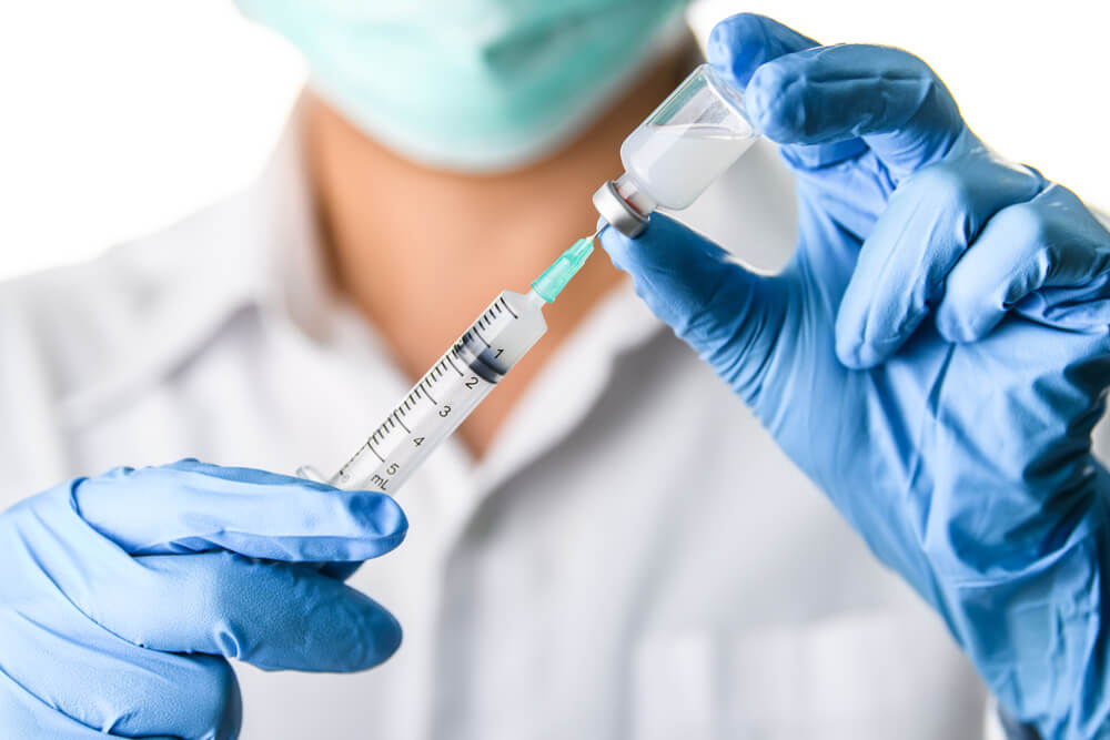 Hand in Blue Gloves Holding a Vaccine