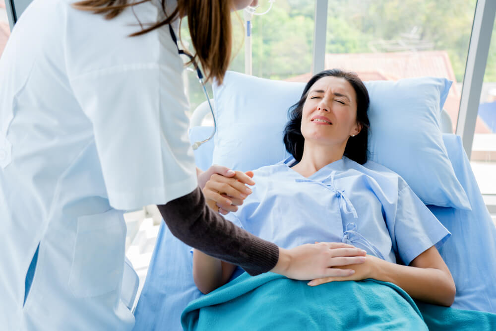 Doctor Is Holding the Patient’s Hand and Pressing the Other Hand on Patient’s Stomach