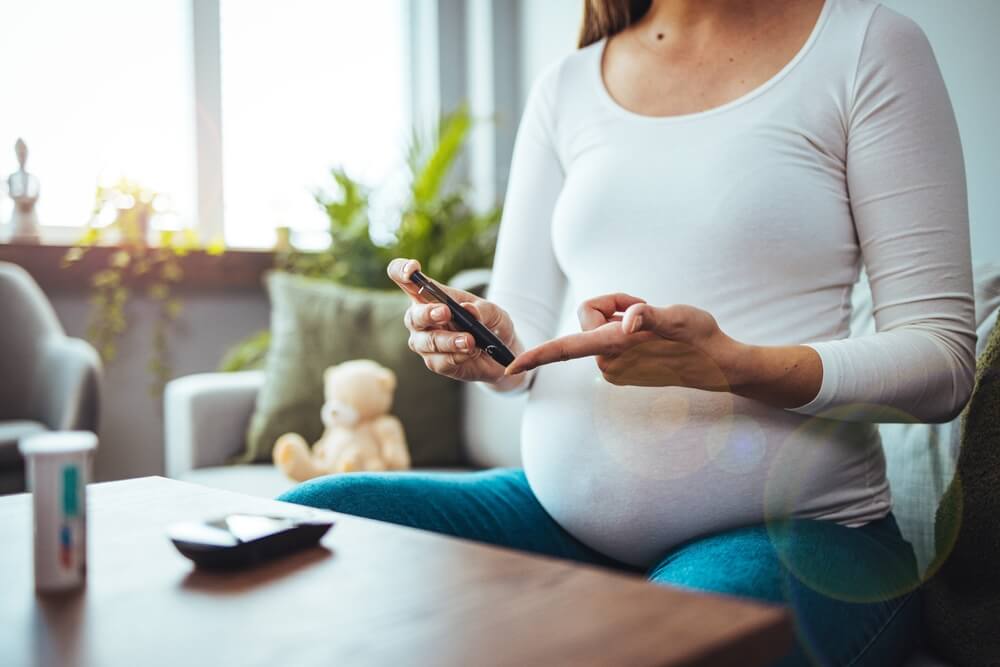 Happy Pregnant Woman With Glucometer Checking Blood Sugar Level at Home. Woman Testing for High Blood Sugar