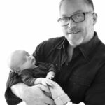 black and white image of a male doctor holding newborn