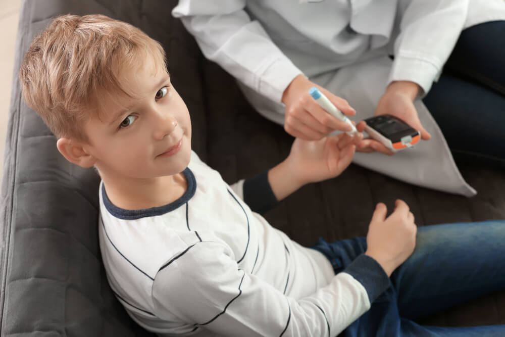 Doctor Using Lancet Pen and Digital Glucometer to Check Diabetic Boy's Blood Sugar Level 