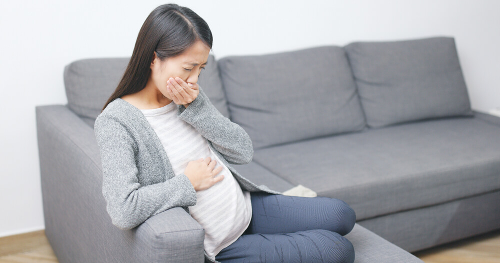 Pregnant Woman Sitting on the Couch Suffering From Nausea