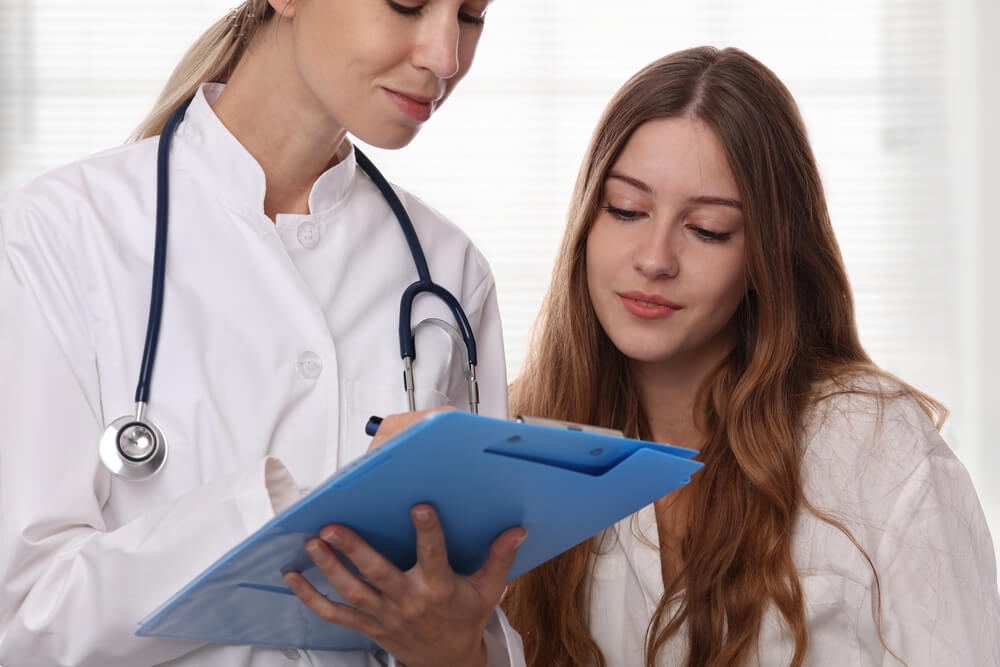 Smiling Female Doctor Showing to Teenage Patient Test Results